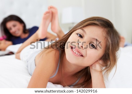 Mother And Children Relaxing In Bed Wearing Pajamas