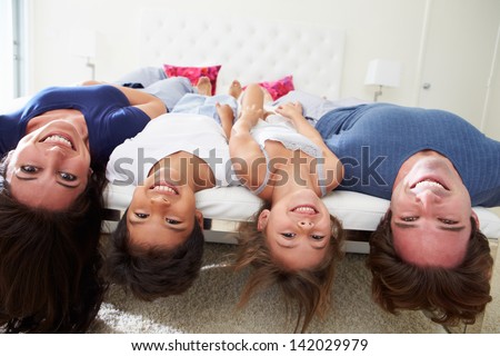 Family Lying Upside Down On Bed In Pajamas Together
