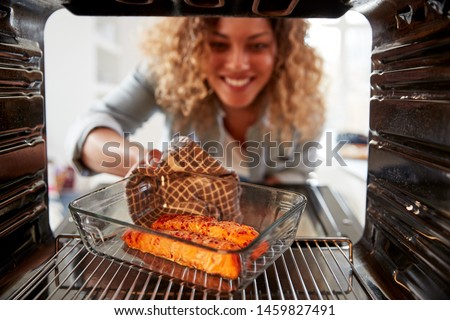 View Looking Out From Inside Oven As Woman Cooks Oven Baked Salmon