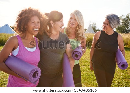 Photo of Group Of Mature Female Friends On Outdoor Yoga Retreat Walking Along Path Through Campsite
