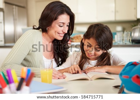 Mother Helping Daughter With Reading Homework At Table