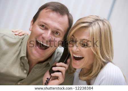 Couple receiving good news over the phone at home