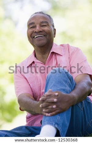 Senior man relaxing in park sitting on grass
