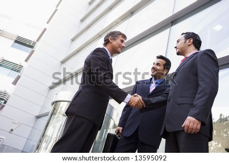 Group of businessmen shaking hands outside office building
