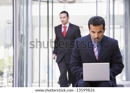 Businessman using laptop outside office