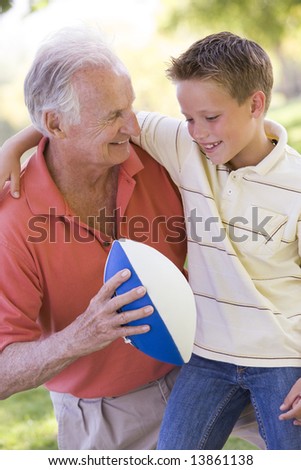 Grandfather and grandson outdoors with football smiling