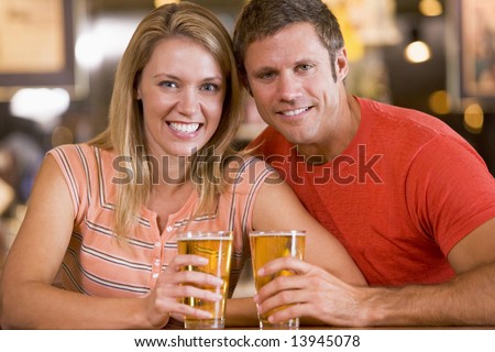 Happy young couple having beers at a bar
