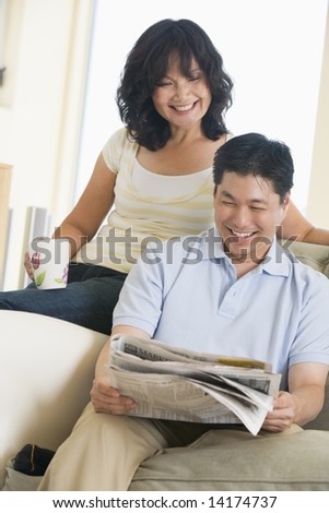 Couple relaxing with a newspaper and smiling