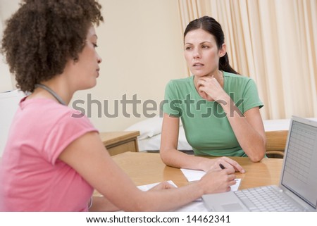 Doctor with laptop and woman in doctor\'s office frowning