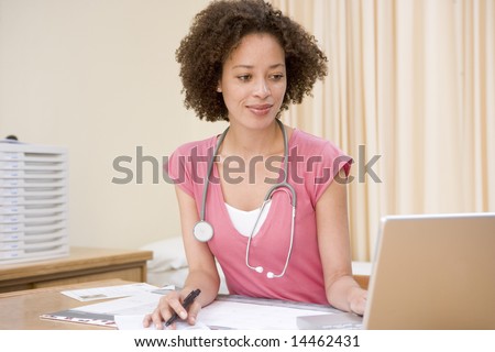 Doctor using laptop in doctor\'s office smiling