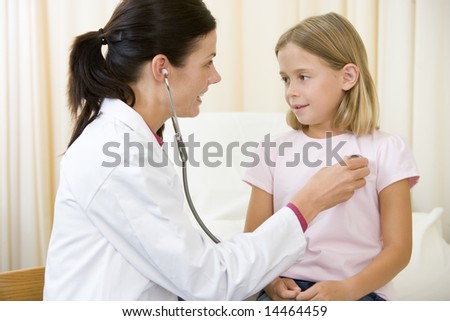 Doctor giving checkup with stethoscope to young girl in exam room