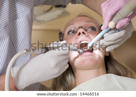 Dentist and assistant in exam room with woman in chair
