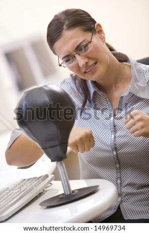 Woman in computer room using small punching bag for stress relief
