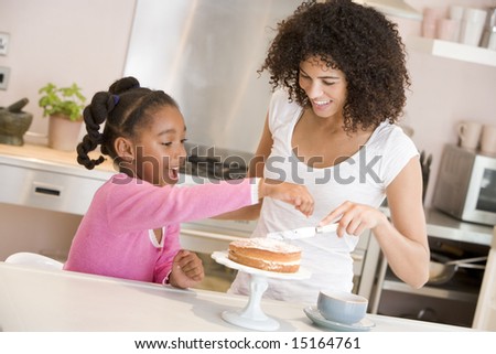 Woman and young girl in kitchen icing a cake smiling