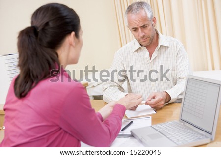 Doctor with laptop and man in doctor\'s office smiling
