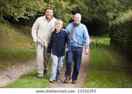 Grandfather walking with son and grandson through woods