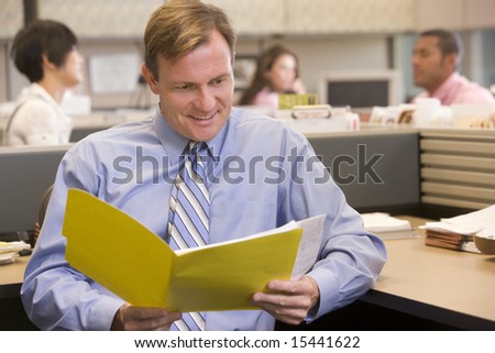 Businessman in cubicle with folder smiling