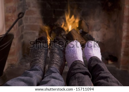 Couple\'s feet warming at a fireplace