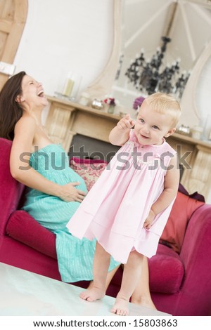 Pregnant mother holding belly in pain with daughter pointing in foreground