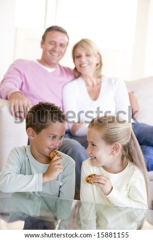 Family sitting in living room eating cookies and smiling