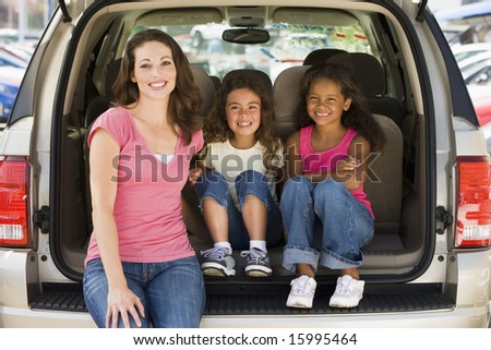 Woman with two young girls sitting in back of van smiling