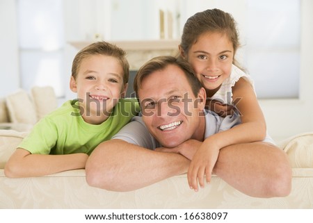 Man and two young children sitting in living room smiling
