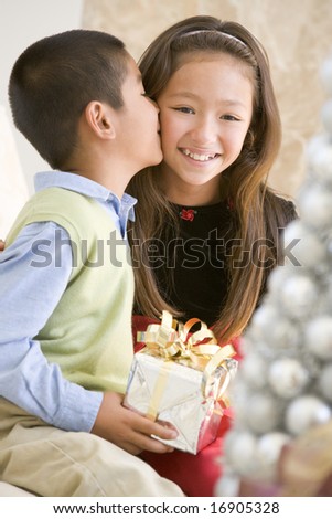 Brother Kissing His Sister On The Cheek,And Holding A Christmas Gift
