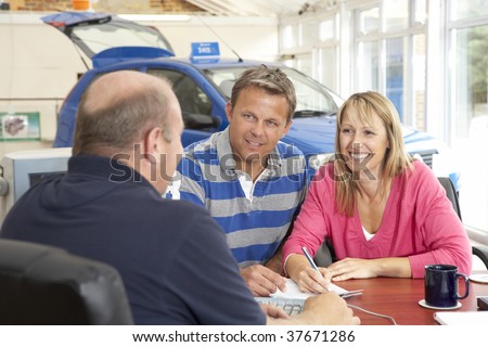 Couple filling in paperwork in car showroom
