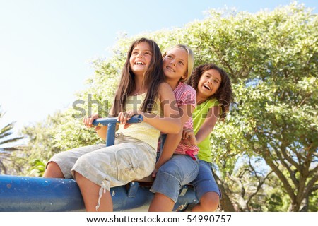 Three Girls Riding On See Saw In Playground