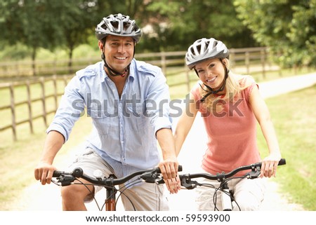 Couple Cycling In Countryside Wearing Safety Helmets