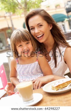 Mother And Daughter Enjoying Cup Of Coffee And Piece Of Cake In Cafe