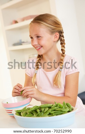 Happy girl splitting peas in kitchen