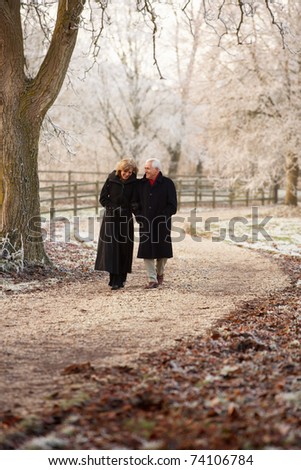 Senior Couple On Winter Walk Through Frosty Landscape