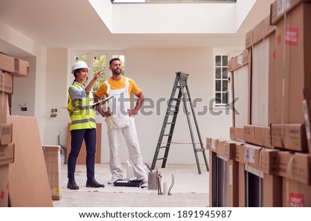 Female Surveyor With Clipboard Meeting With Decorator Working Inside Property Stock fotó © 