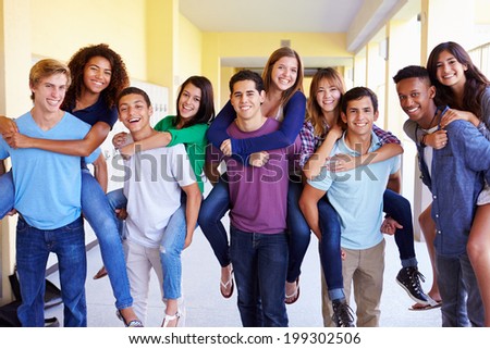 Group Of High School Students Giving Piggybacks In Corridor