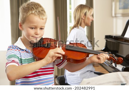 Young boy playing violin accompanied by teacher