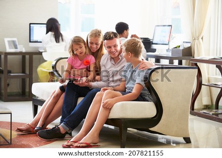 Family In Hotel Lobby Looking At Digital Tablet