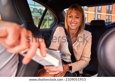 Mature Businesswoman In Back Of Taxi Paying Fare Using Contactless Payment App On Mobile Phone Stock foto © 