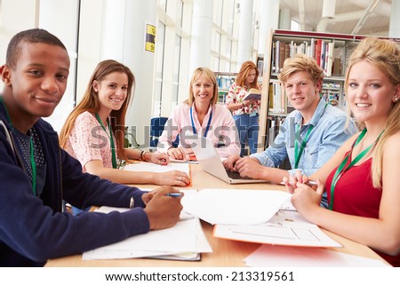 Group Of Students Working Together In Library With Teacher