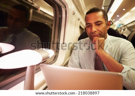 Businessman Commuting To Work On Train And Using Laptop At Night