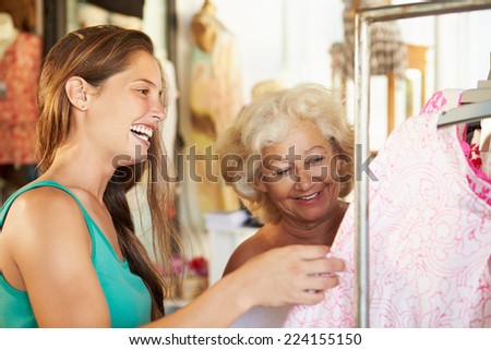 Sales Assistant Showing Senior Female Customer Clothes