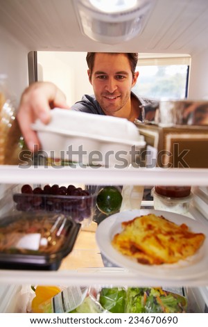 Man Looking Inside Fridge Filled With Food And Choosing Eggs