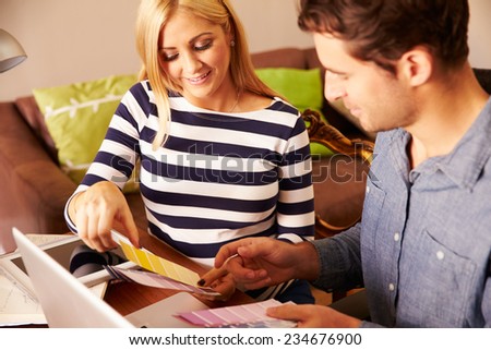 Couple Sitting At Computer Looking at Paint Sample Charts
