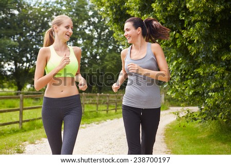 Two Female Friends On Run In Countryside Together
