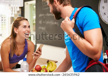 Couple Wearing Gym Clothing Talking In Kitchen