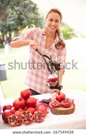 Woman Juicing Fresh Pomegranates At Farmers Market Stall
