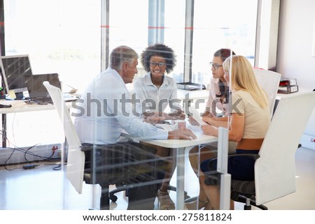 Four colleagues meeting around a table in an office
