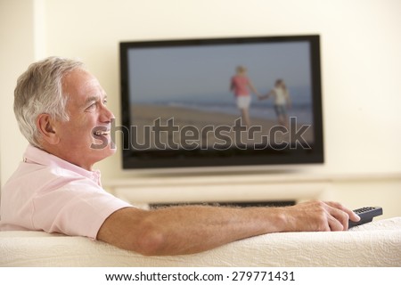 Senior Man Watching Widescreen TV At Home