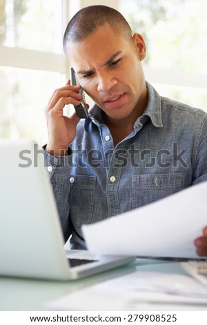 Frustrated Young Man On Phone Using Laptop At Home
