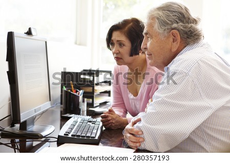 Senior Hispanic couple working on computer at home